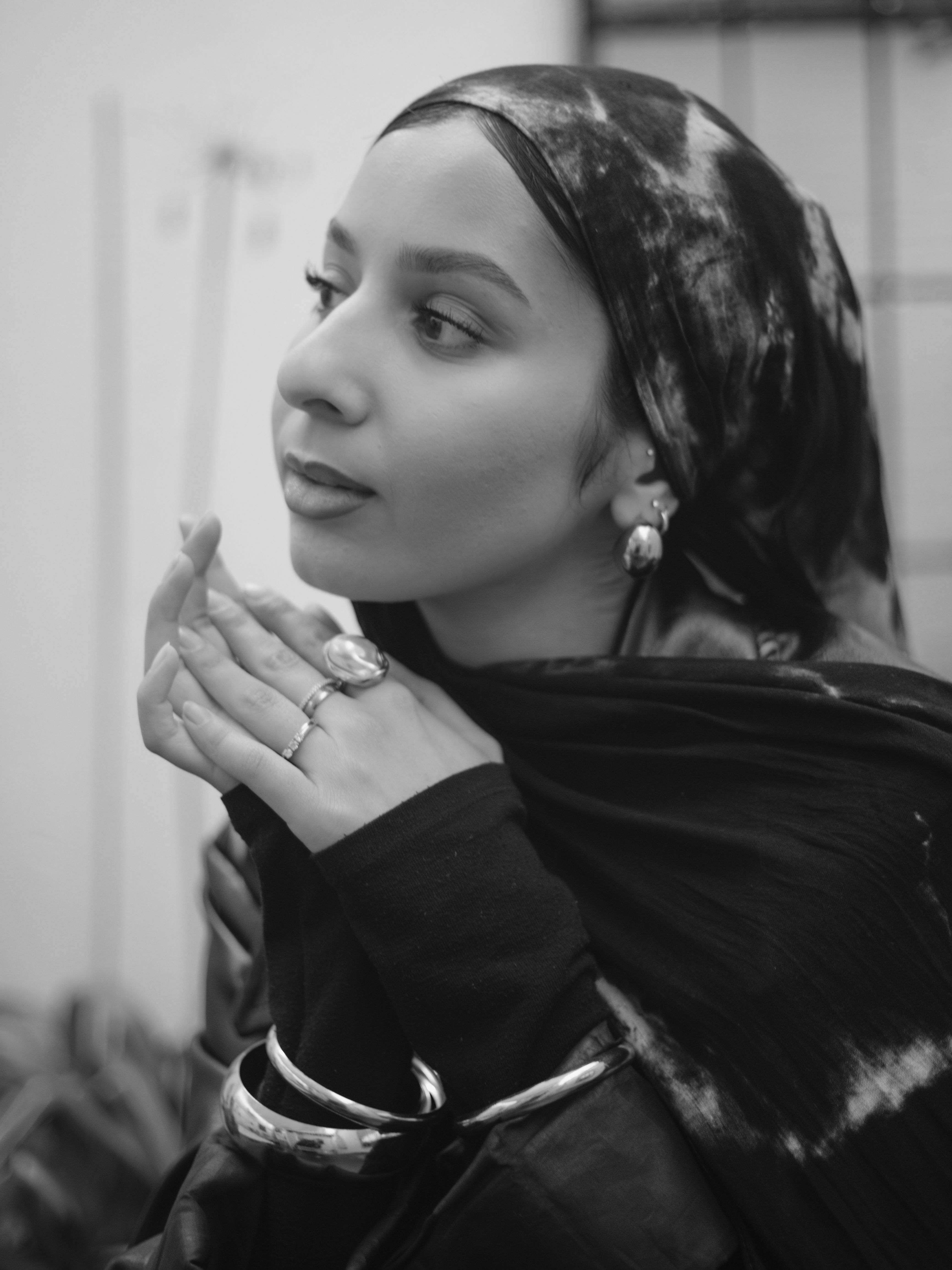 Black-and-white profile portrait of Furvah Shah, hands at chin, contemplative.